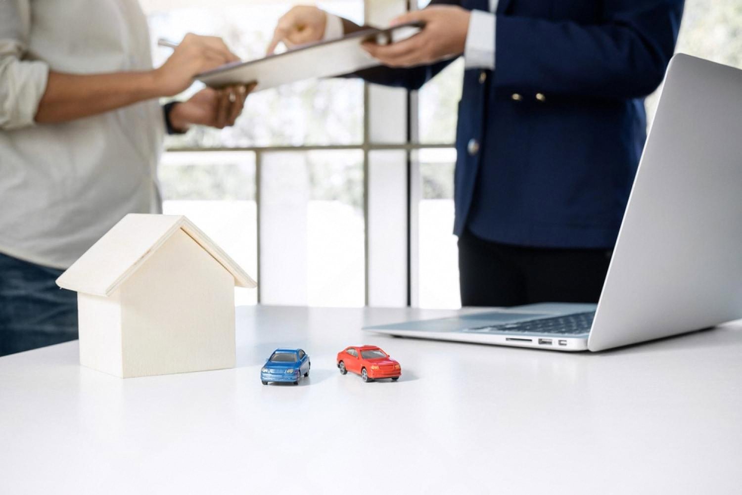 Insurance agent reviewing a car policy with a client next to two model cars
